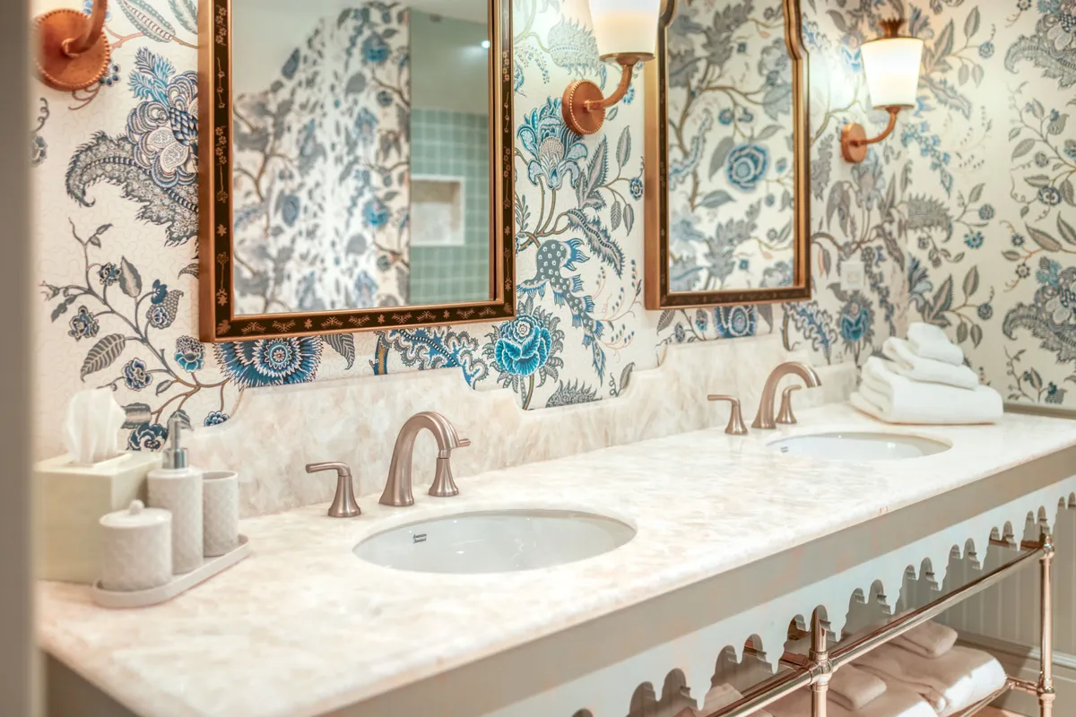 An elegant bathroom scene with double sinks, ornate mirrors, and lavish decorative wallpaper. The space exudes a spa-like ambiance ideal for unwinding, pampering, and self-care routines.